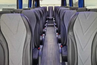 Interior of a premium tourist bus with comfortable seating and vibrant lighting.