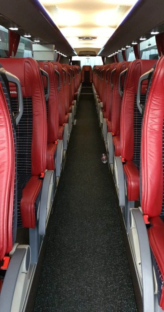 Vue intérieure d'un bus VanHool avec des sièges rouges confortables et un design spacieux.