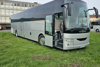 Exterior view of a VanHool bus parked on a grassy field, showcasing its elegant design.