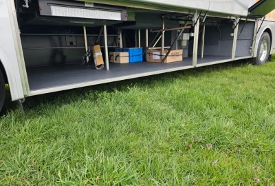Spacious luggage compartment of a VanHool bus with organized storage space.