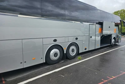Side view of a VanHool bus with open luggage compartments for easy access to storage areas.