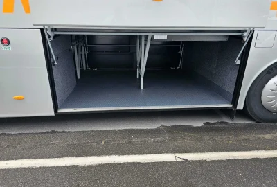 Open luggage compartment of a VanHool bus showcasing spacious and accessible storage design.