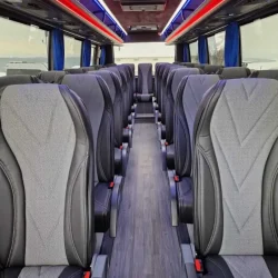Interior of a premium tourist bus with comfortable seating and vibrant lighting.