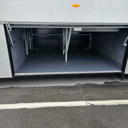 Open luggage compartment of a VanHool bus showcasing spacious and accessible storage design.